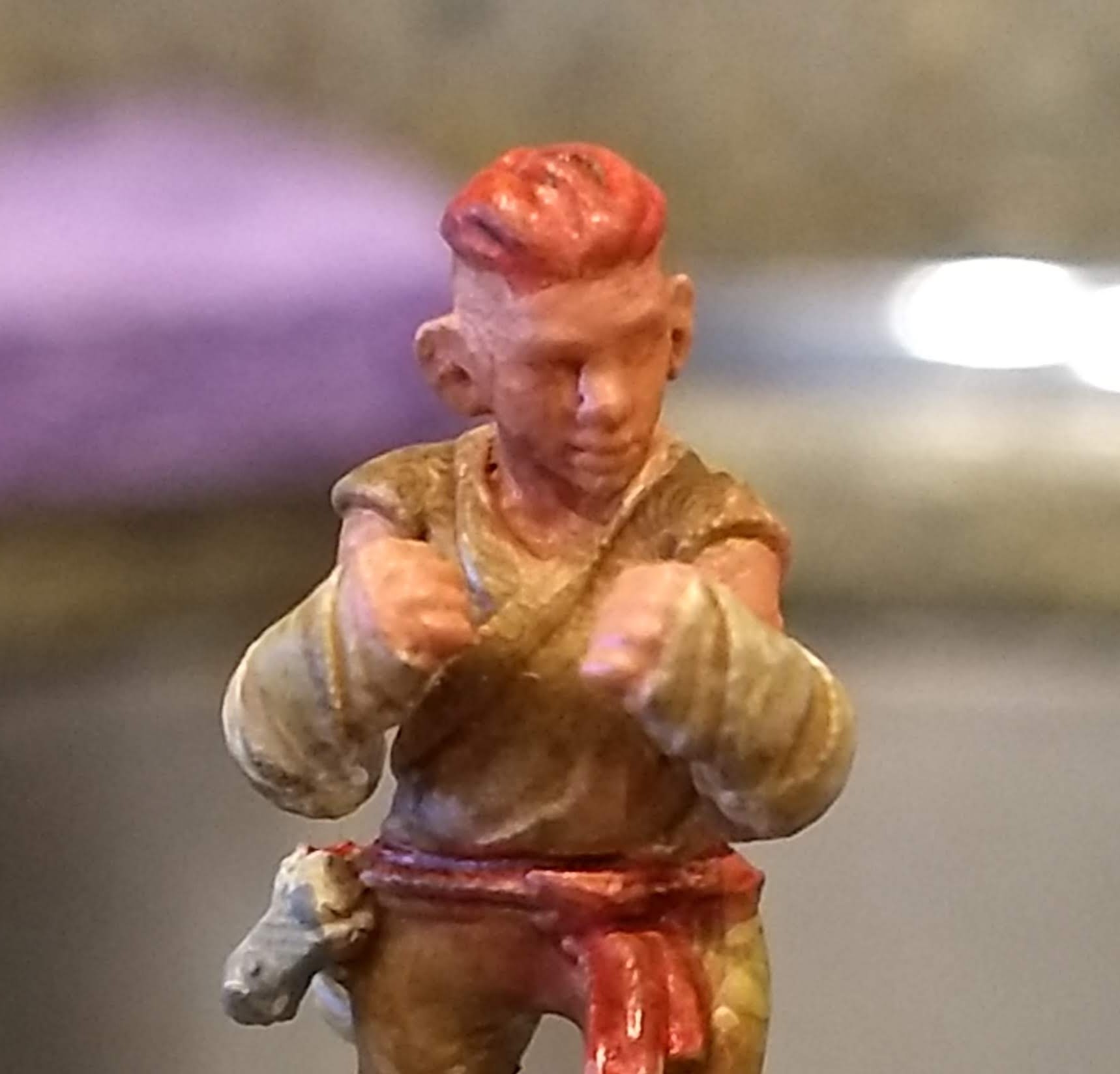 Close-up photo of a Dungeons & Dragons miniature, representing a dwarven monk with red hair and a side-shave